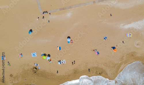 Canvas Print Aerial view of a sandy beach line full of bathers and colorful umbrellas
