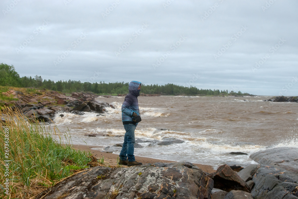 A man stands on the shore watching the sea in stormy weather