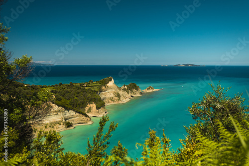 Cape Drastis (Peroulades) with crystal clear blue water on a sunny summer day with leaf foreground (Corfu, Greece, Europe)