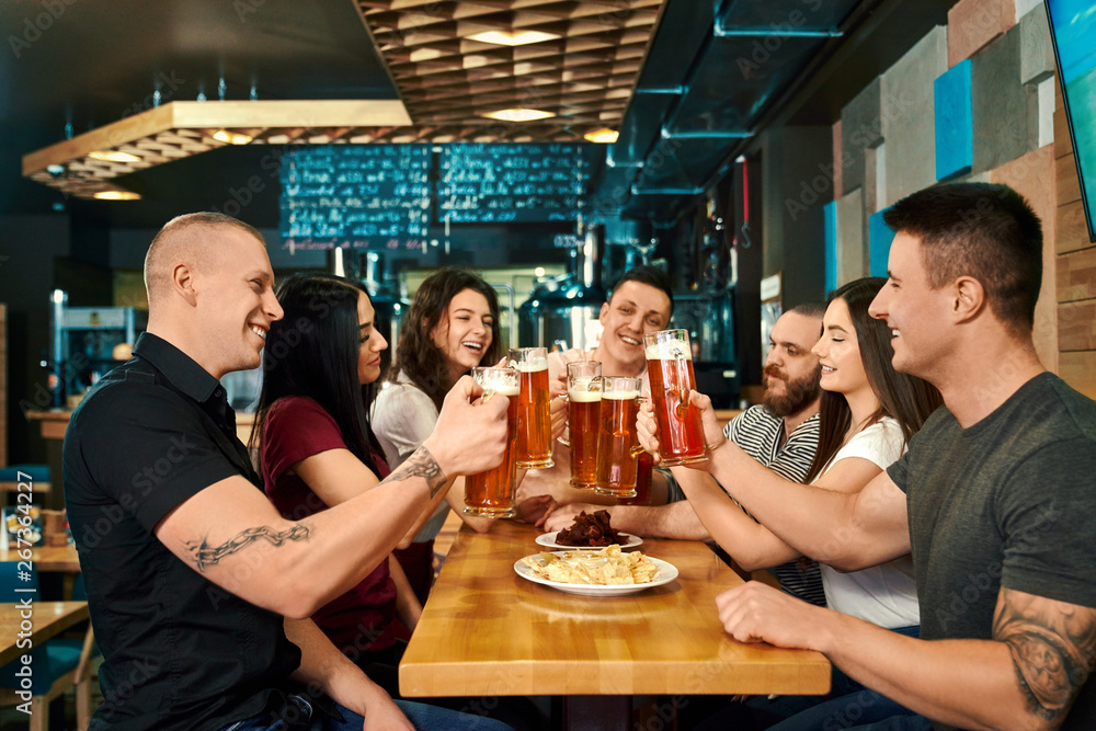 Company sitting at big table and enjoying ale in pub