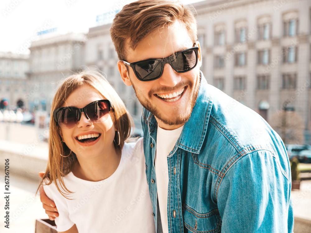 Smiling beautiful girl and her handsome boyfriend in casual summer clothes. Happy cheerful family having fun on the street background in sunglasses.