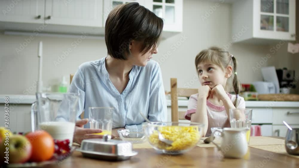 mother talking with her daughter sitting at dinner table mother talking with her daughter sitting at dinner table