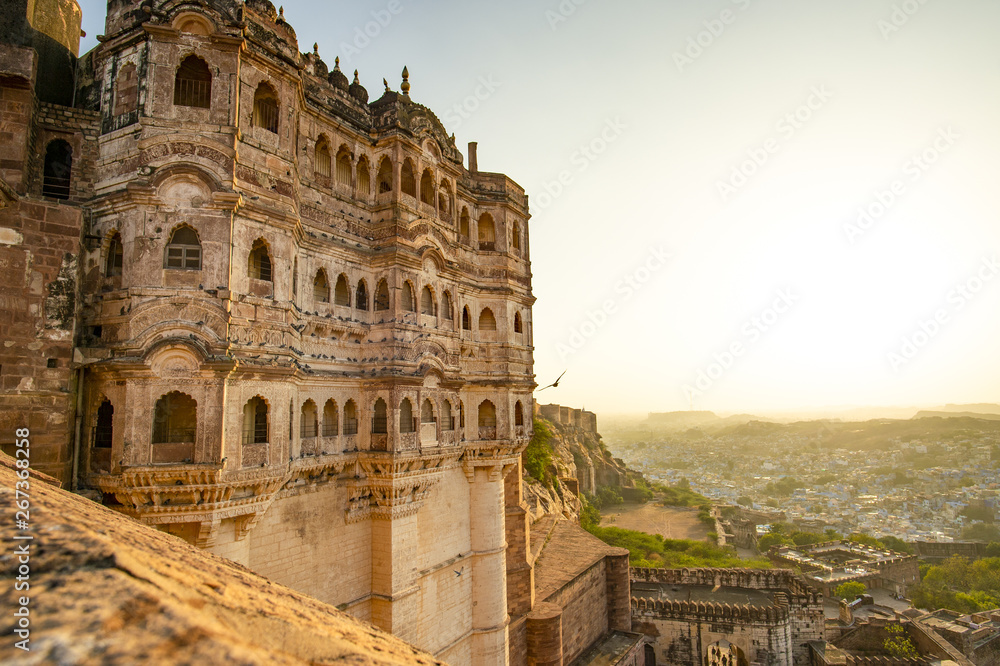 Fototapeta premium Wspaniały widok na starożytny fort Mehrangarh podczas pięknego zachodu słońca z niebieskim miastem Jodhpur w tle, Rajasthan, Indie. Mehrangarh (Fort Mehran) to jeden z największych fortów w Indiach.