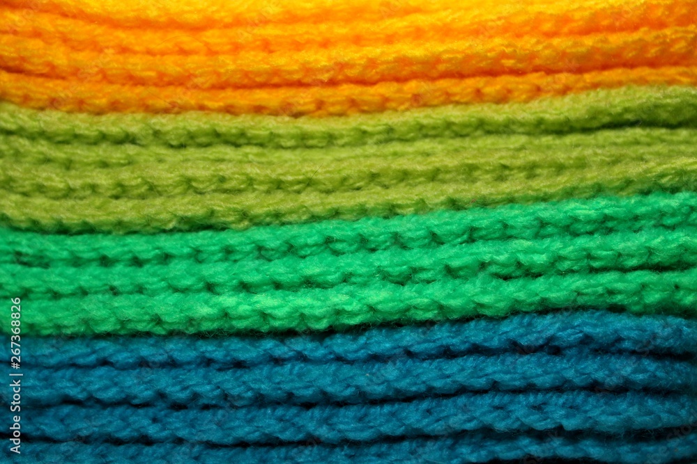 Colorful yellow, green and blue design background of knitted woolen elements in a pale