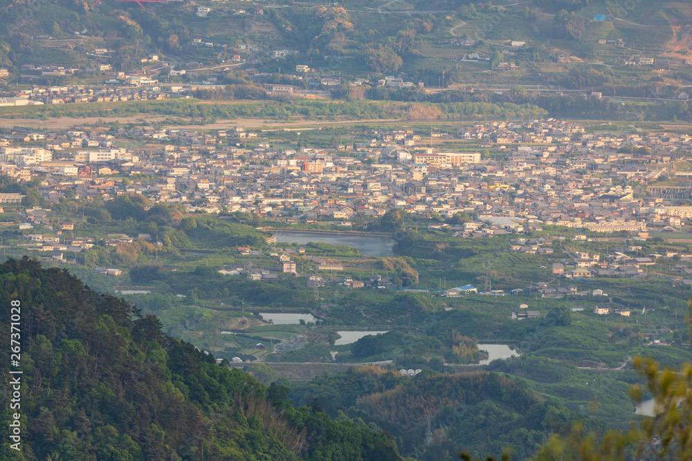 Looking down on a small town in green valley as late afternoon sun cast light on buildings