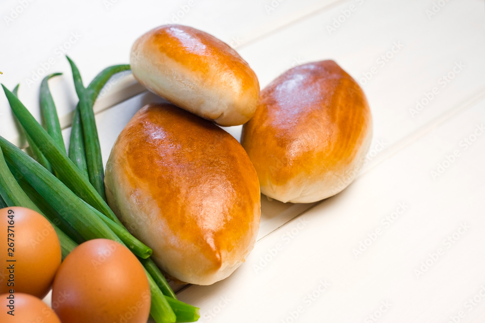 patties with egg and onions on a white wooden background. sweet cakes with filling. green onions patties with egg and onions on a white wooden background. sweet cakes with filling. green onions