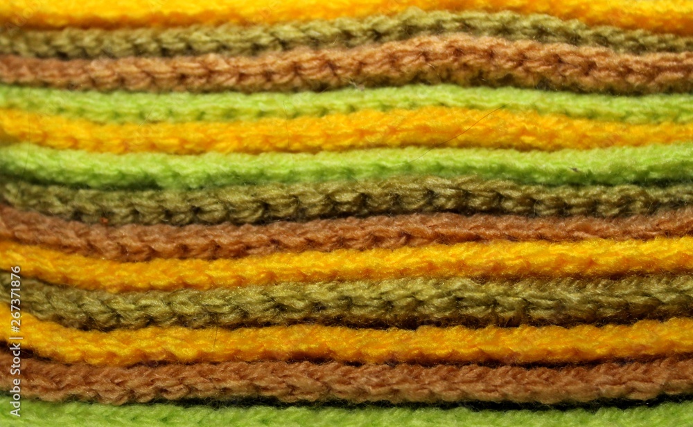 Colorful yellow, green and brown design background of knitted woolen elements in a pale