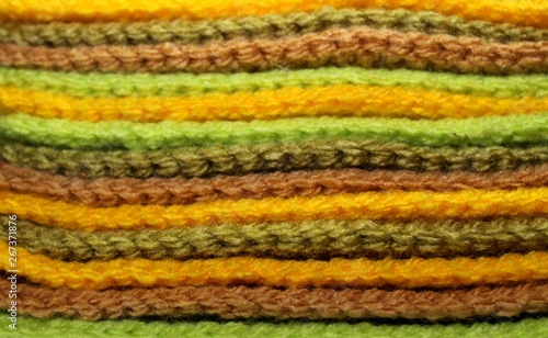 Colorful yellow, green and brown design background of knitted woolen elements in a pale © lipchania