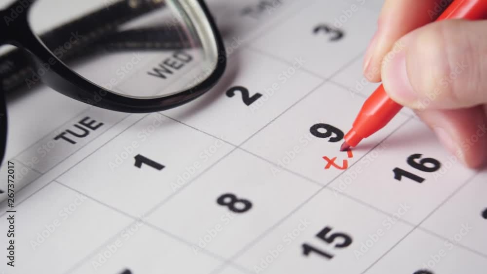 Signing a day on a calendar with red pen or marker. Writing word test under 9th day of a month Signing a day on a calendar with red pen or marker. Writing word test under 9th day of a month