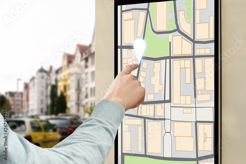 A man presses a finger on a street touchscreen with city map. Smart city concept