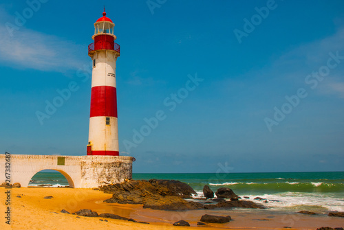 SALVADOR, BAHIA, BRAZIL: Farol De Itapua on the rough sea. Lighthouse on the beach in Sunny weather. photo