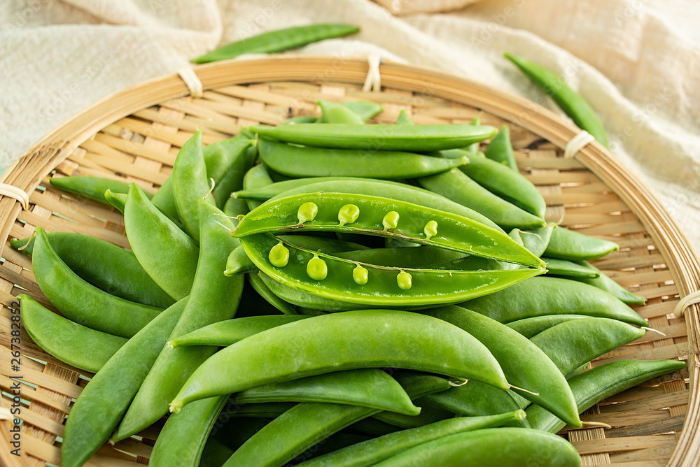 Fresh bean pod vegetable sweet beans on a bamboo sieve on a light green background Fresh bean pod vegetable sweet beans on a bamboo sieve on a light green background