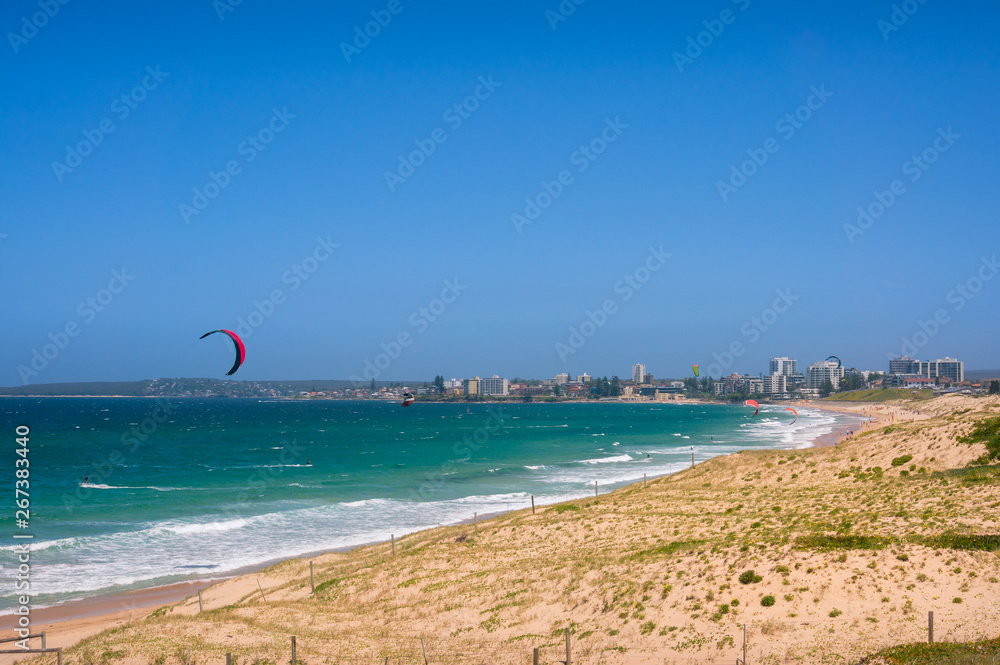 Panoramic beach with colorful kite surfers parachutes