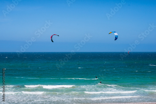 Open ocean landscape with kite surfers with colorful parachutes