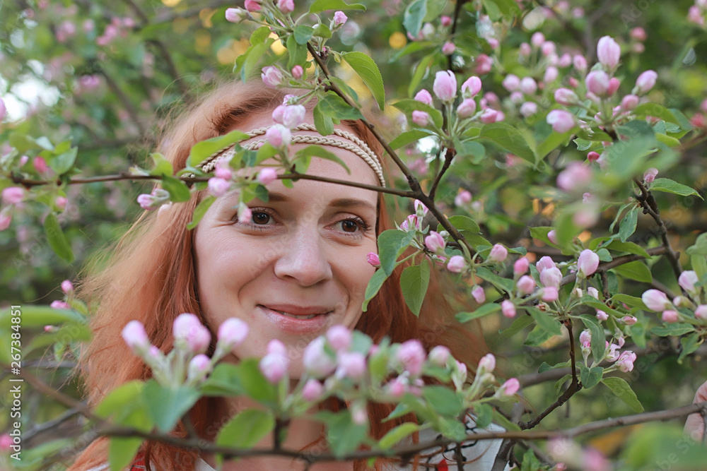 A girl on a walk in an autumn park. Young red-haired girl in the spring on nature.