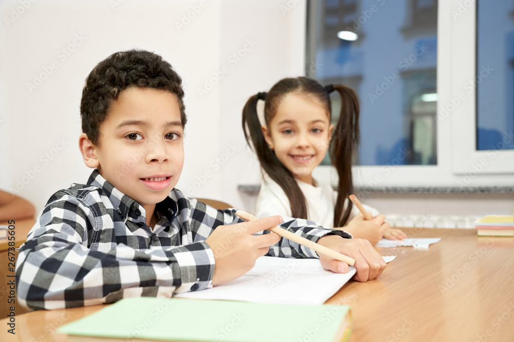 Boy and girl sitting at desk in classroom, posing. Boy and girl sitting at desk in classroom, posing.