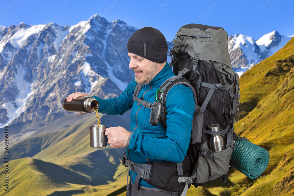 Happy man traveler pours tea in a mug on the background of beautiful scenery