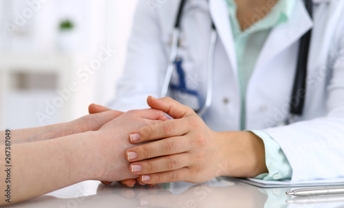 Hand of a doctor woman reassuring to female patient  close-up. Medical ethics and trust concept