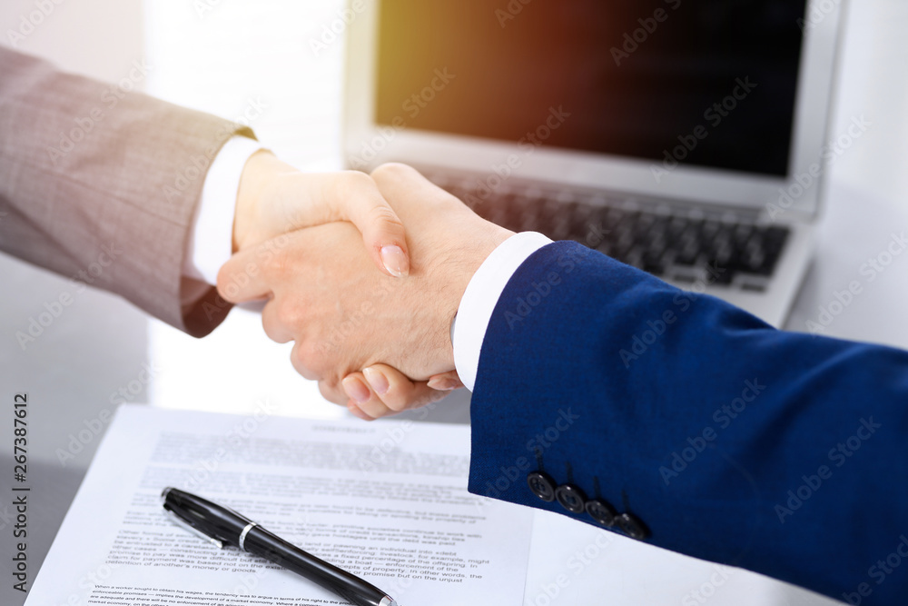 Businessman and business woman shaking hands to each other above signed contract. Success at negotiation and agreement  concept