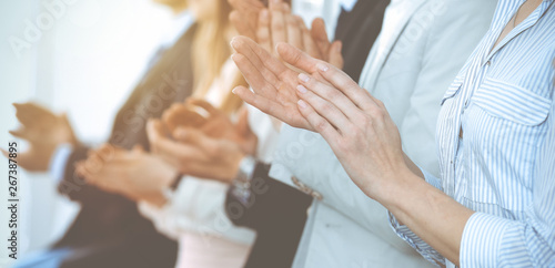 Business people clapping and applause at meeting or conference, close-up of hands. Group of unknown businessmen and women in modern white office. Success teamwork or corporate coaching concept photo