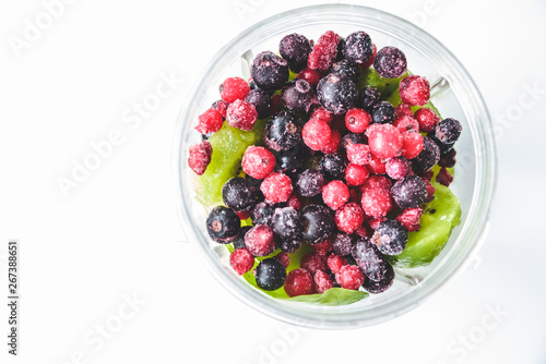 Flat lay of a blender and fresh seasonal berries and fruits over white background, preparing smoothies, detox, healthy clean eating. Summer drinks.