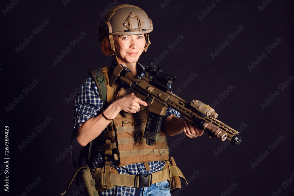 Female civil in tactical uniform with rifle. Shot in studio on black background. Woman citizen forced to defend herself Female civil in tactical uniform with rifle. Shot in studio on black background. Woman citizen forced to defend herself