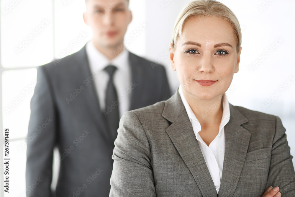 Business woman standing straight with colleague businessman in office, headshot. Success and corporate partnership concept Business woman standing straight with colleague businessman in office, headshot. Success and corporate partnership concept