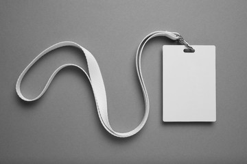 Empty layout layout on grey background. Common blank label name tag hanging on neck with thread.