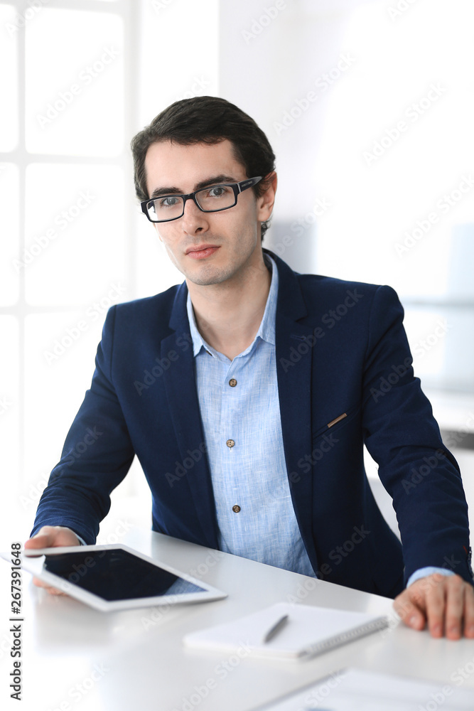 Businessman working with tablet computer in modern office. Headshot of male entrepreneur or company manager at workplace. Business concept Businessman working with tablet computer in modern office. Headshot of male entrepreneur or company manager at workplace. Business concept