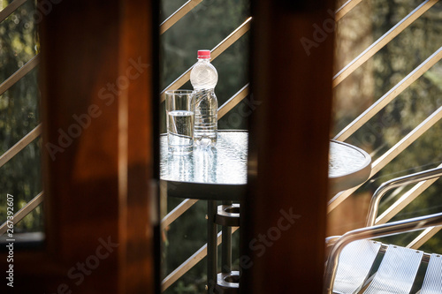Glass of water and plastic bottle on balcony coffee table