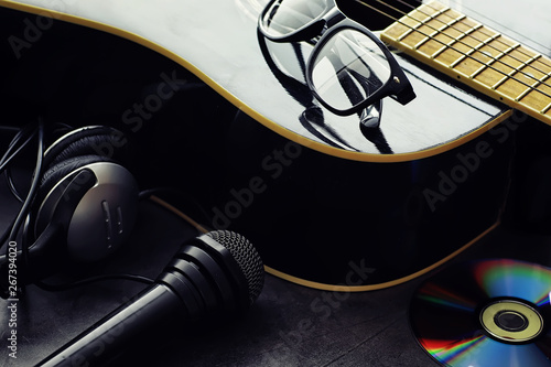 Guitar and accessories on a stone background. Desk musician, headphones, microphone. photo