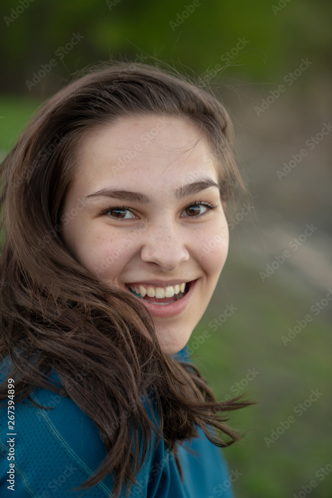 Teen girl in teal blue shirt outside in summer