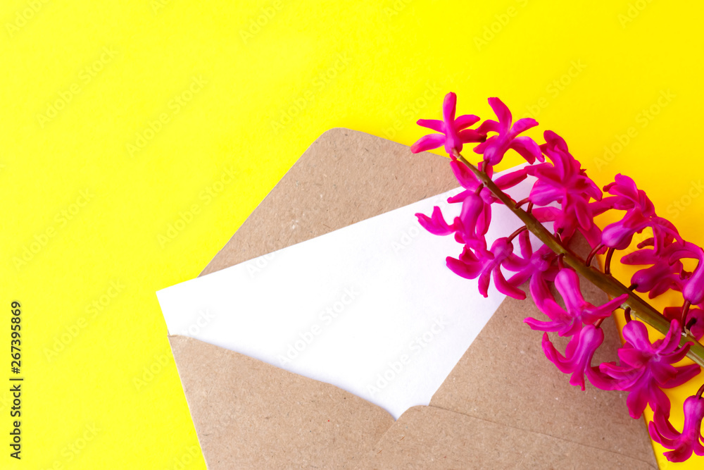 Love envelope with blank letter and pink hyacinth flowers with pink hearts on bright yellow bacground. Copy space Love envelope with blank letter and pink hyacinth flowers with pink hearts on bright yellow bacground. Copy space