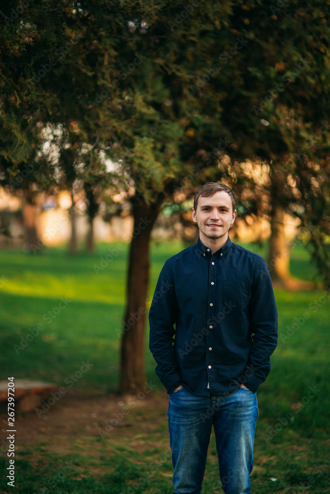Man in dark blue shirt standing in the park Man in dark blue shirt standing in the park