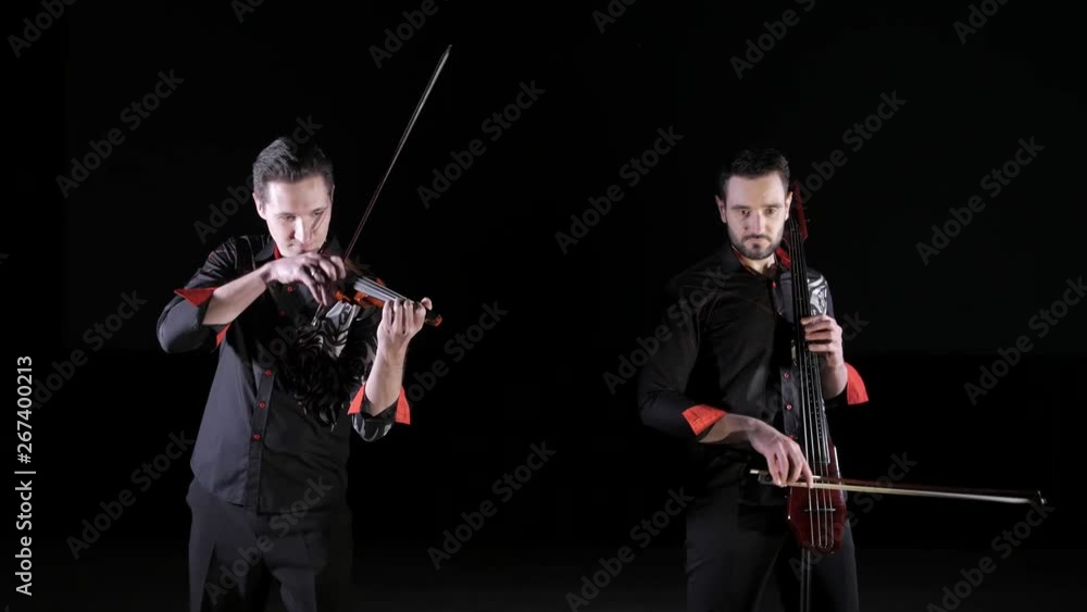 duet of young men playing electric cello and electric violin on a black background, isolated duet of young men playing electric cello and electric violin on a black background, isolated