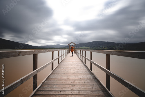 Wooden bridge across lake on cloudy day long exposure