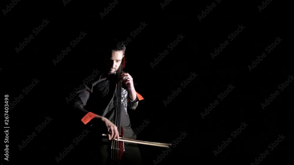 young handsome man plays electric cello on black background, isolated young handsome man plays electric cello on black background, isolated