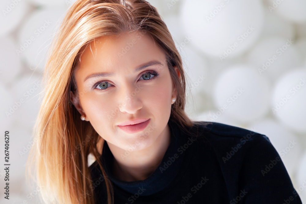 Cute beautiful pretty attractive romantic girl in black sweater looking at camera, female beauty portrait with makeup in rays of sun against background of white balloons in photostudio Cute beautiful pretty attractive romantic girl in black sweater looking at camera, female beauty portrait with makeup in rays of sun against background of white balloons in photostudio