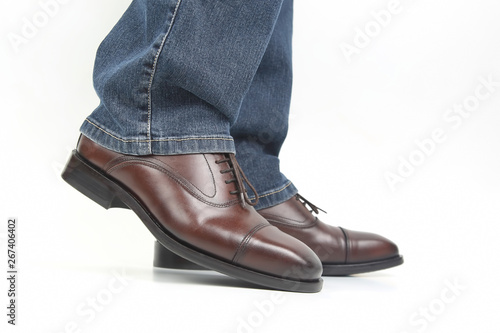 Men's legs in jeans shod in classic brown shoes