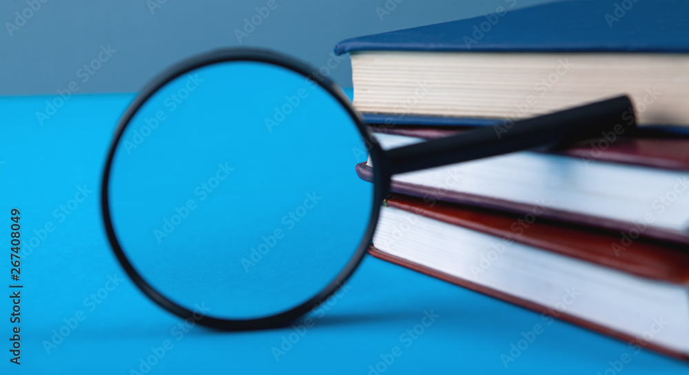 books and magnifier on blue background books and magnifier on blue background