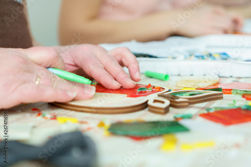 The artist maker mosaic in a wooden harvesting. Female hands closeup collect mosaic of colored stones. Human activity to workplace
