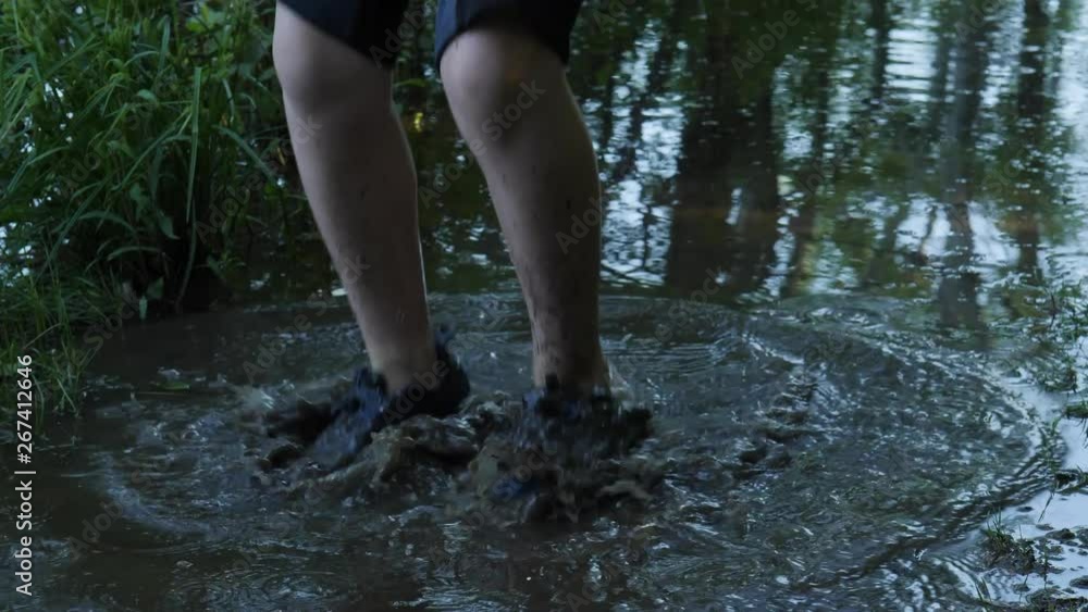 kid walking and jumping in a forest mud puddle kid walking and jumping in a forest mud puddle
