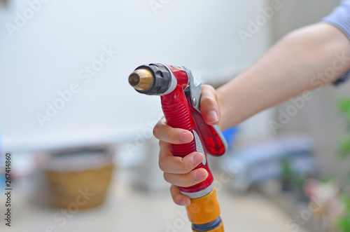 A red water spray gun with rubber hosepipe