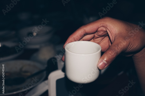 Hand holding a white ceramic tea cup. Drinking after a sumptuous meal for digestion. Selective focus. Copy space.