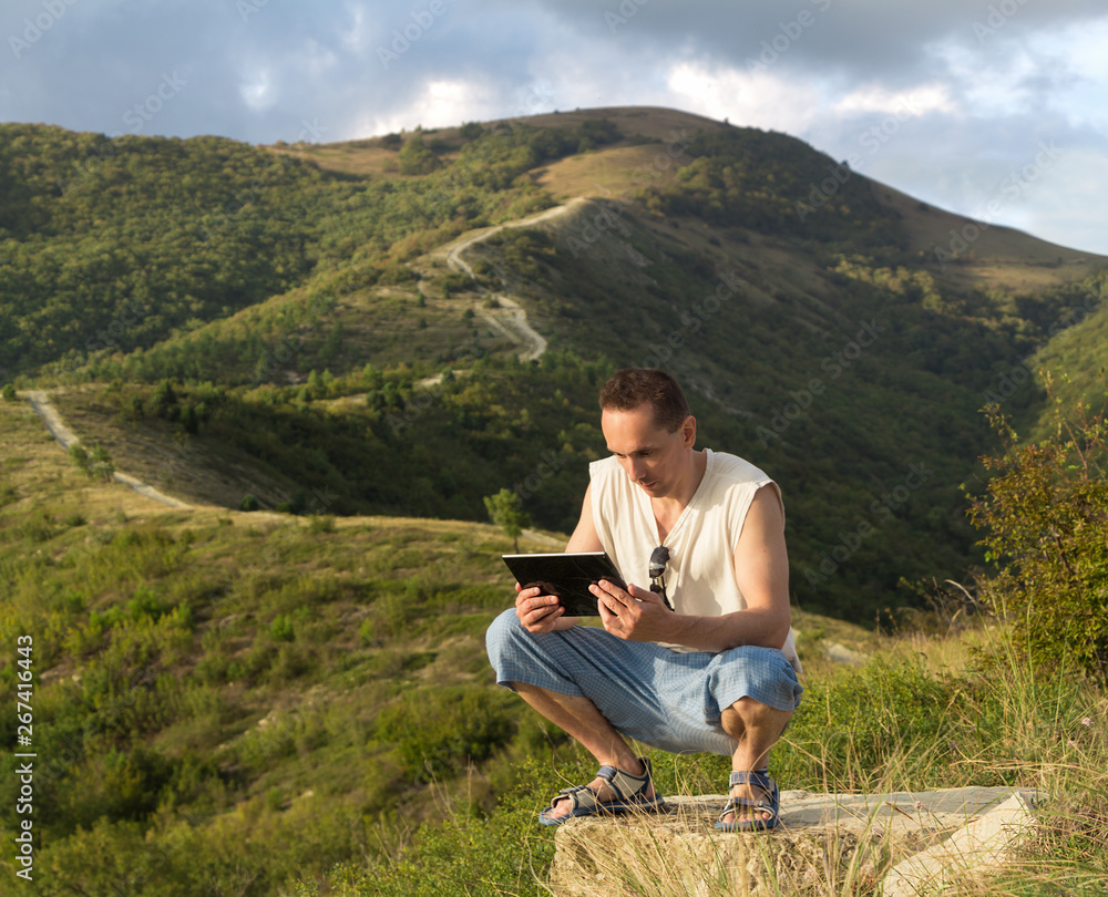 A man in the mountains with tablet computer, world wide web