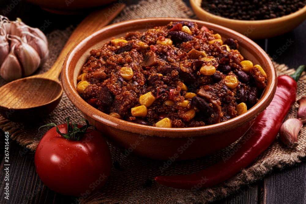 Mexican quinoa warm salad, chili, vegetarian food on dark wood background.