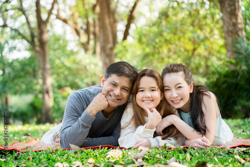 Concept Father and Mother's Day. Asian family is Sitting and chatting the park for Summer which is ideal for long weekend vacations. Taking care of family makes children feel the love of parenting.