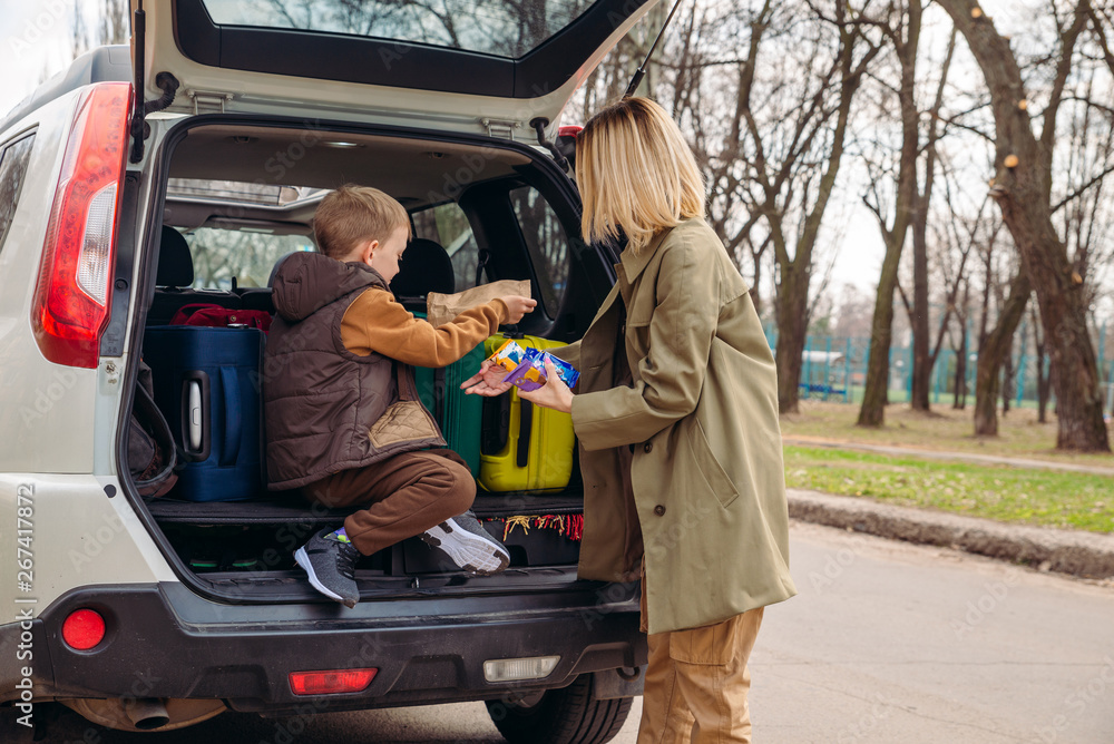 little kid sitting with mother in car trunk full of luggage eating chocolate candies little kid sitting with mother in car trunk full of luggage eating chocolate candies