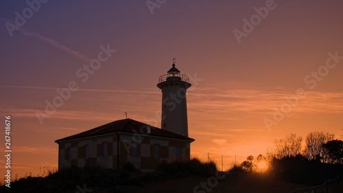 The lighthouse at sunset on the beach at the mouth of the river Tagliamento, Bibione, Venezia, Italy.