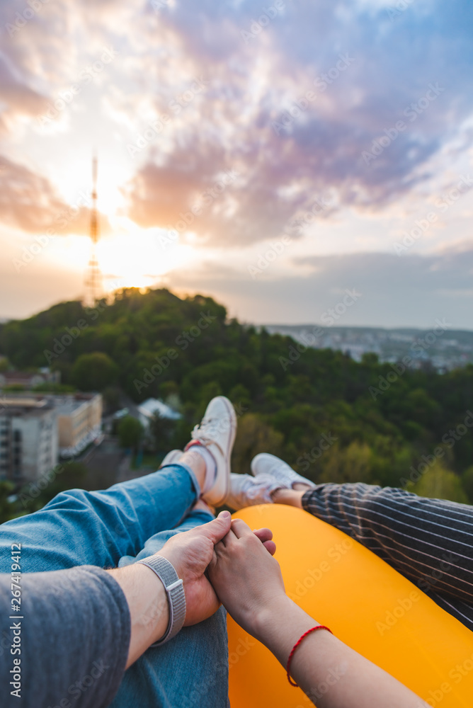 couple laying and enjoying view of sunset over the city - obrazy, fototapety, plakaty 